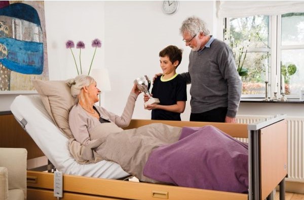 Woman sitting in electric hospital bed at home